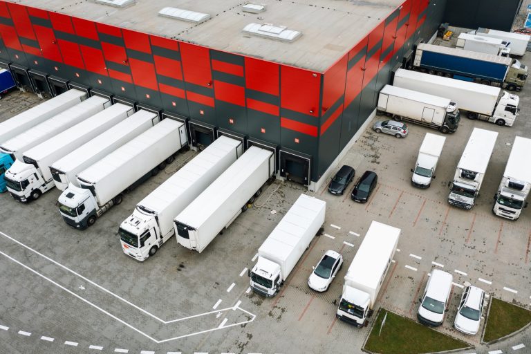 Widok z góry na bazę transportową z naczepami przy rampach, monitoring naczep
